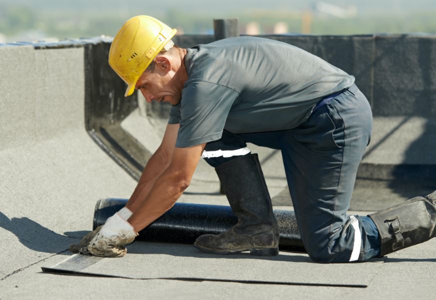 A man is performing flat roof services in NJ