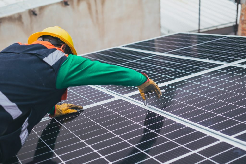 A man is performing solar roof repairing services on roof